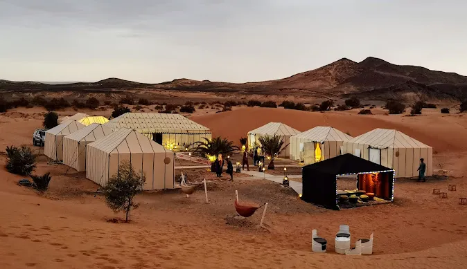 A group of tents in the desert near Merzouga, with people gathered around them, enjoying the surroundings.
marrakech to merzouga