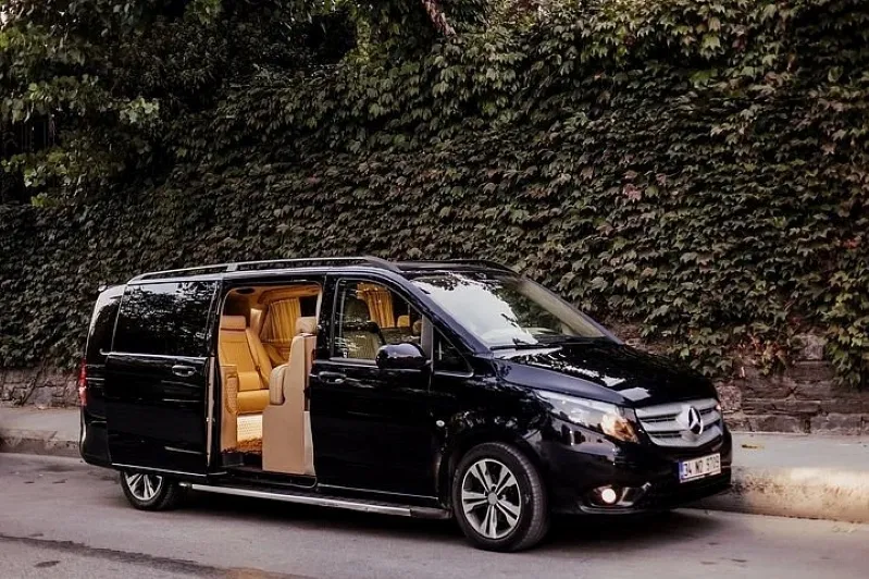 A black Mercedes van parked on the roadside, promoting Casablanca Tours - Day Excursions & Airport Transfers.