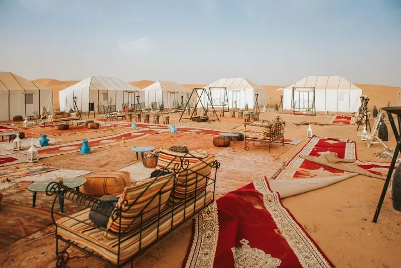 A panoramic view of the Moroccan desert adorned with tents and furniture, highlighting the charm of guided tours.