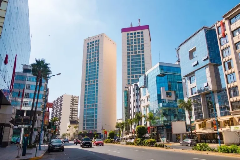 A cruise ship illuminated at night, docked in a harbor with city lights reflecting on the water in Casablanca.