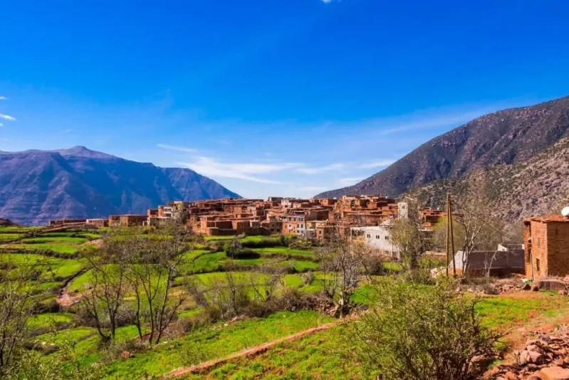 A scenic view of the village of Atlas in Morocco, showcasing traditional architecture against a mountainous backdrop.