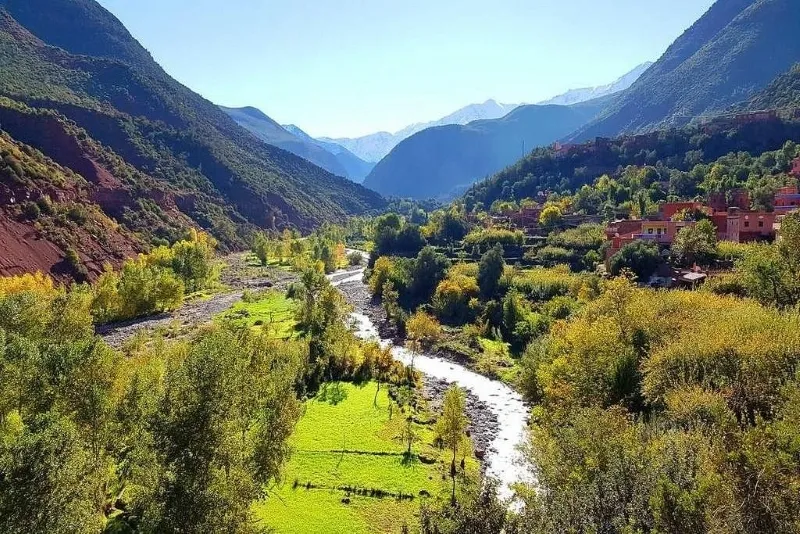 A river flows through a valley surrounded by the rugged peaks of the Atlas Mountains in Morocco.