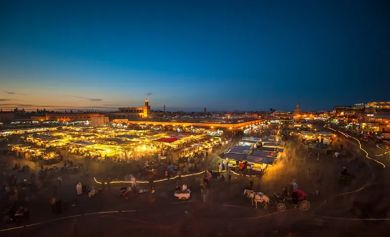 Night view of Marrakech, showcasing illuminated buildings and vibrant street life, highlighting top attractions in the city. between top things to do in Marrakech