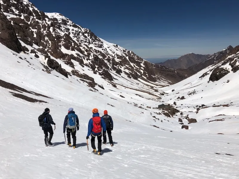 Four people trekking in Morocco Atlas Mountains in the Atlas Mountains of Morocco, surrounded by a winter landscape.
