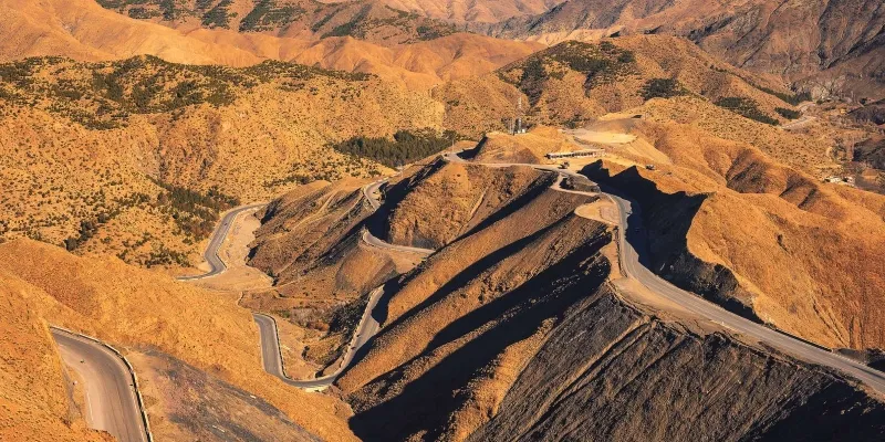 Aerial view of a winding mountain road, showcasing the rugged terrain during a desert tour in Marrakech.
