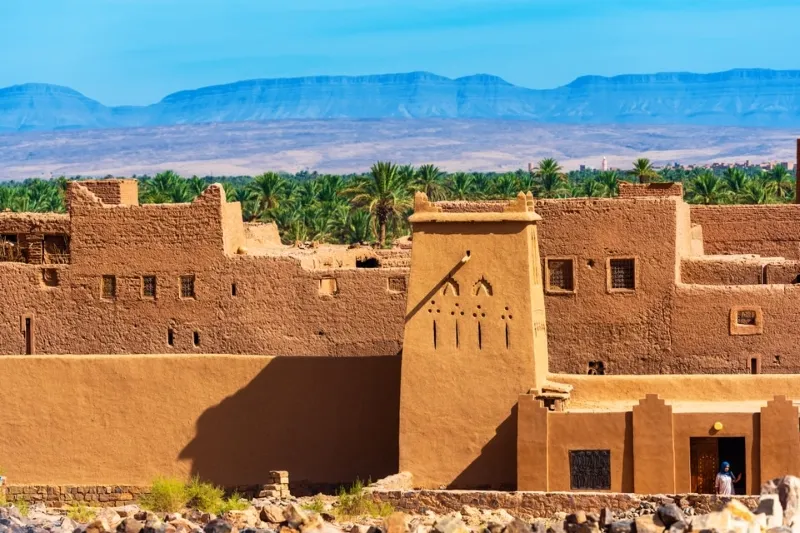 Traditional Marrakech desert tours architecture featuring adobe structures and intricate patterns against a sandy landscape.