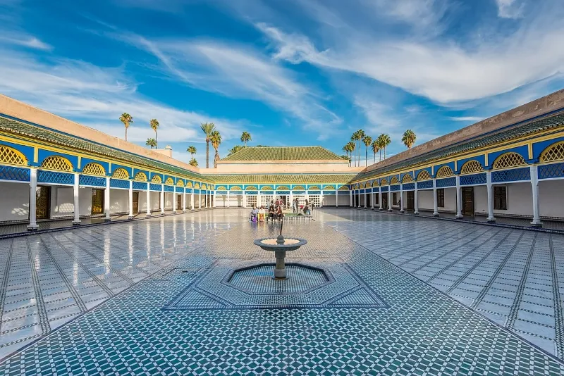 The serene courtyard of the Sultan's Palace in Marrakech, featuring ornate designs and vibrant plants typical of Moroccan culture.