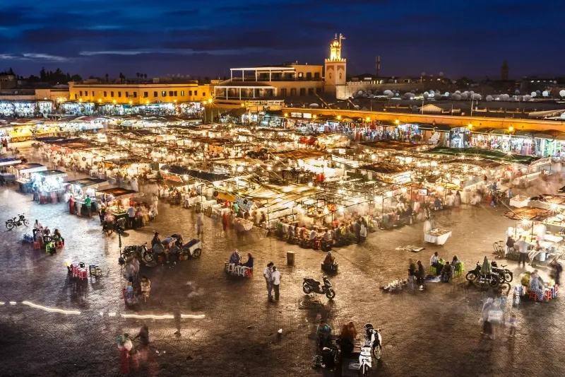Nighttime market in Marrakech, Morocco, bustling with vibrant stalls and colorful lights, showcasing local culture and goods.Between best Marrakech things to see 