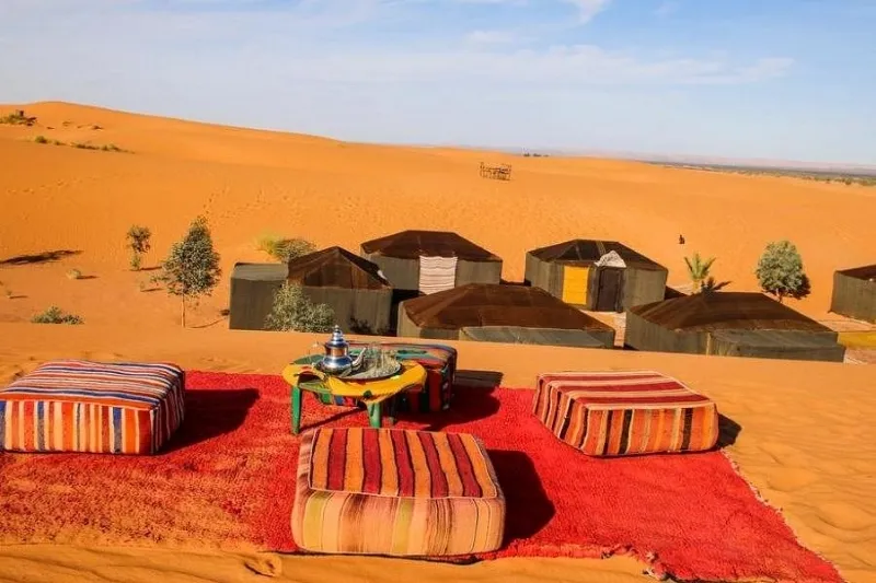 A vibrant rug placed in the Merzouga desert, contrasting with the sandy landscape of the Merzouga desert camp.
