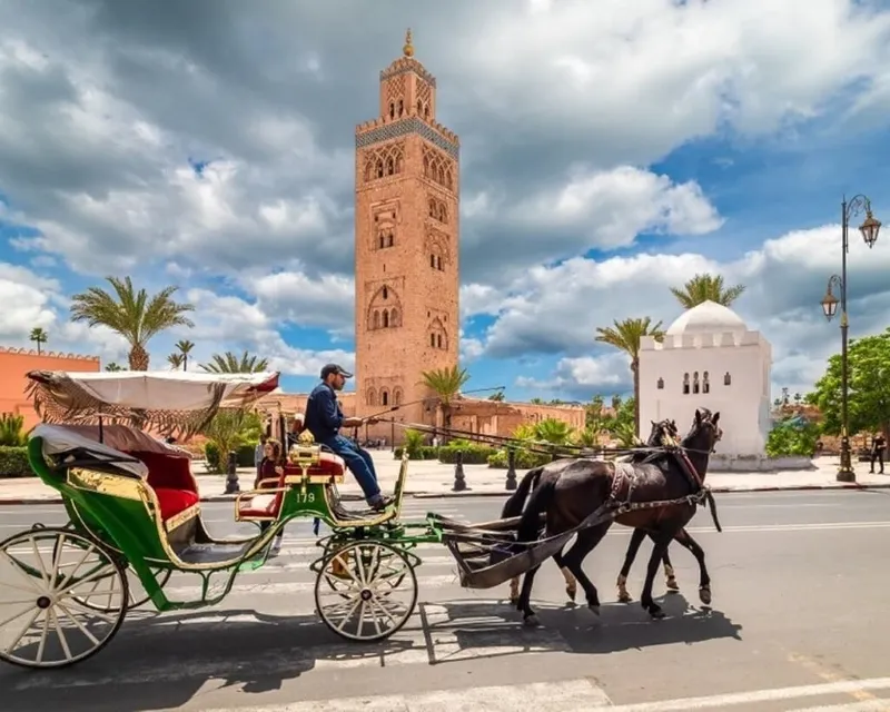 A horse and carriage parked in front of a clock tower, showcasing a scenic view of desert tours in Marrakech.