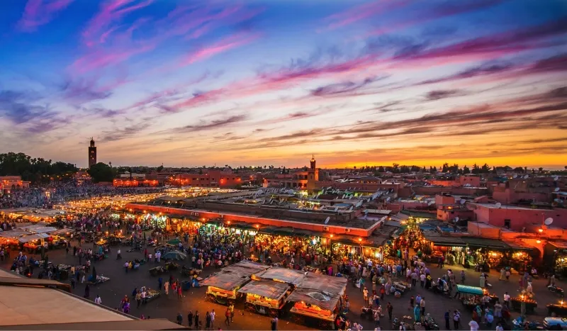 Sunset over Marrakesh, casting warm hues across the city skyline, ideal for Morocco desert tours enthusiasts.