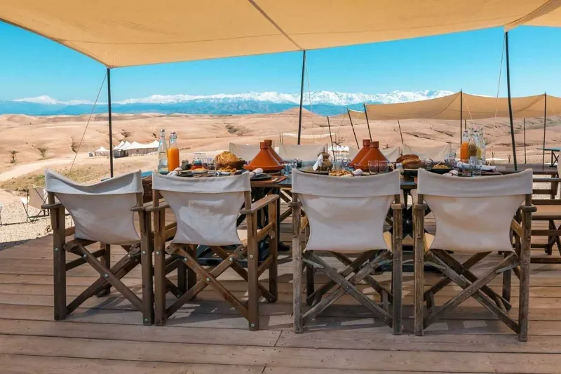 A table set on a deck with a view of the desert, ideal for enjoying desert tours in Marrakech.