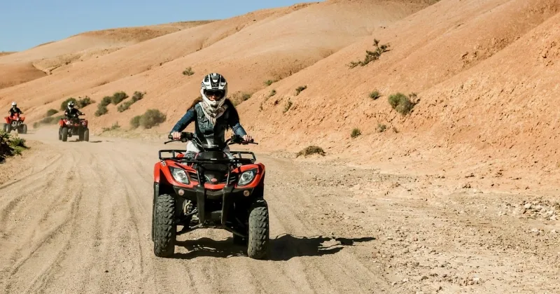 Four individuals riding ATVs through a sandy desert landscape during a Quad Marrakech adventure.