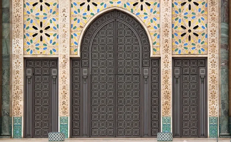 The ornate entrance to a Moroccan mosque, showcasing intricate tile work and architectural details.