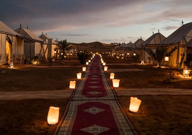 A winding path in the Morocco desert tour , adorned with glowing candles, creating a magical ambiance under the night sky.
