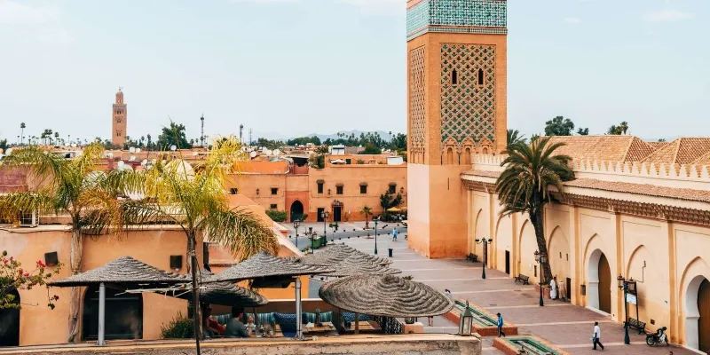 A vibrant view of Marrakech, Morocco, showcasing the bustling Souk with colorful stalls and traditional architecture.

